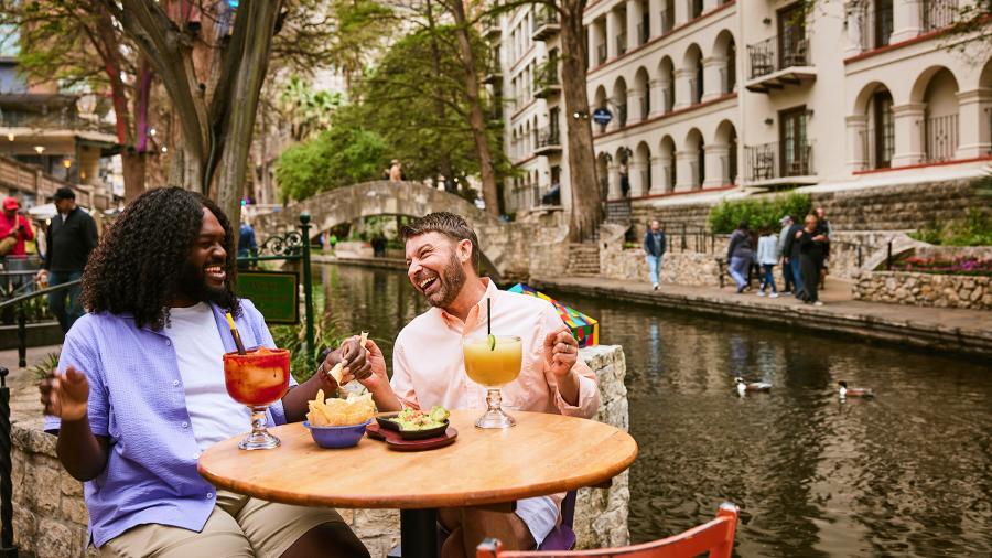 Two men on the River Walk enjoying chips and margaritas