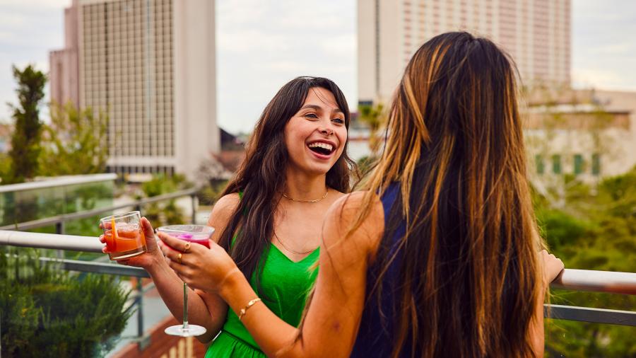 Two girls holding drinks and laughing