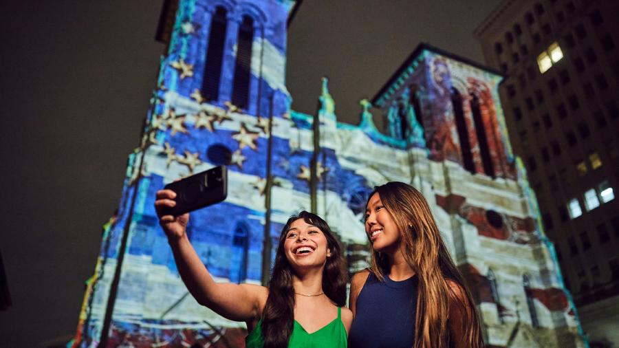 Two girls in front of light show projection