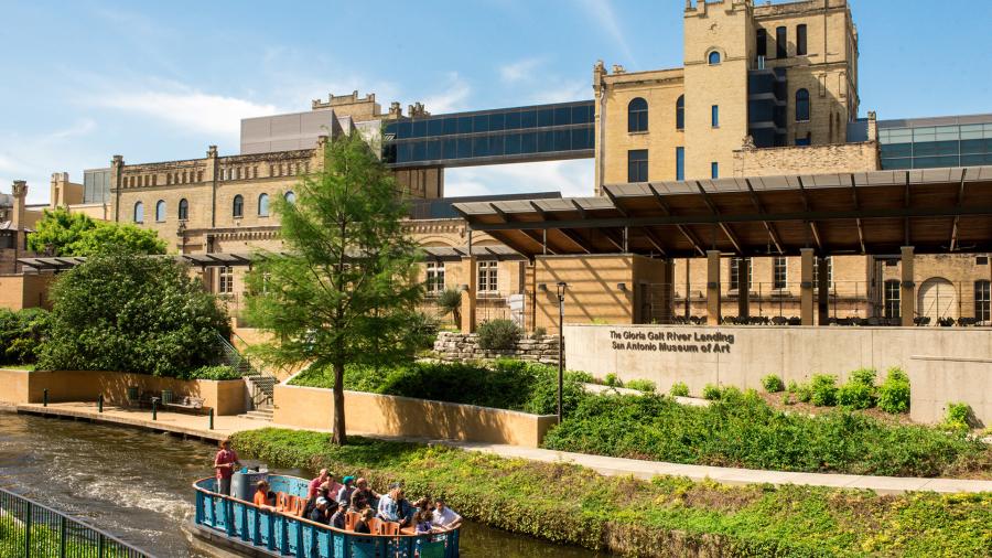 River barge drifting along river in front of San Antonio Museum of Art