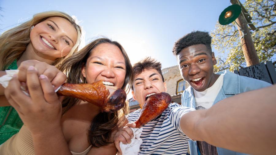 Group of friends taking a selfie and eating turkey legs.