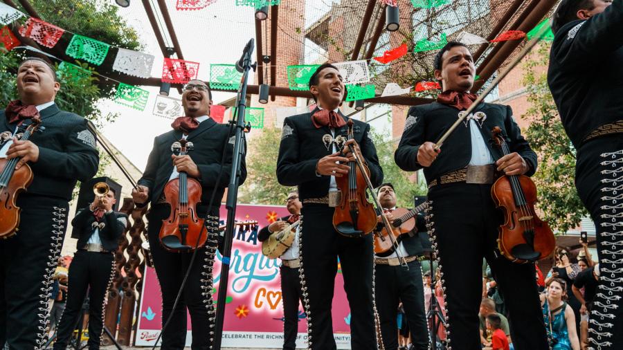 Mariachis standing in front of papel picado