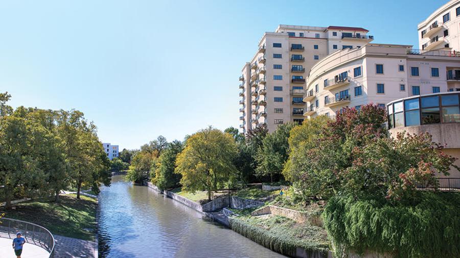 Exterior view of hotel building with River Walk running in front of it.