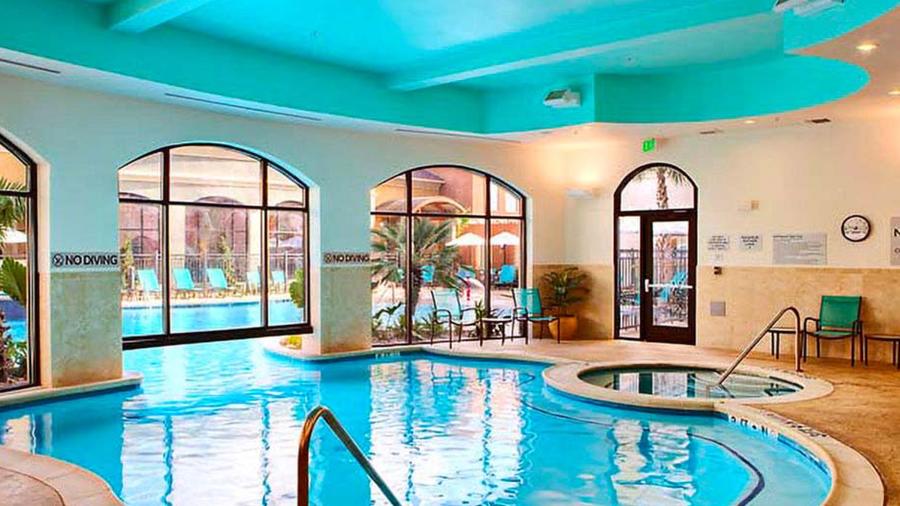Indoor hotel pool with large window in background.