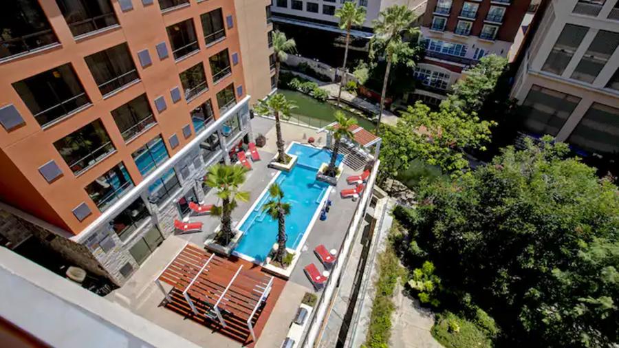 Bird's eye view of hotel pool with surrounding trees.