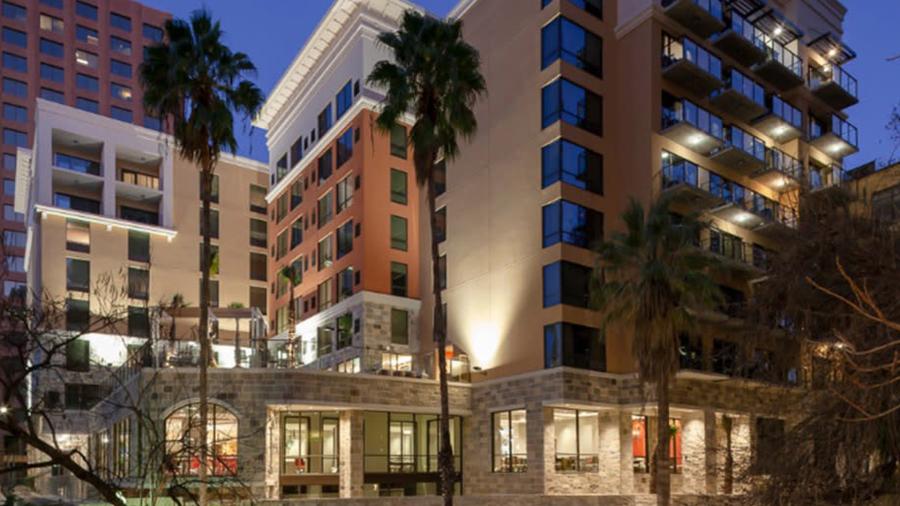 Exterior of hotel lit up at night and two tall palm trees.