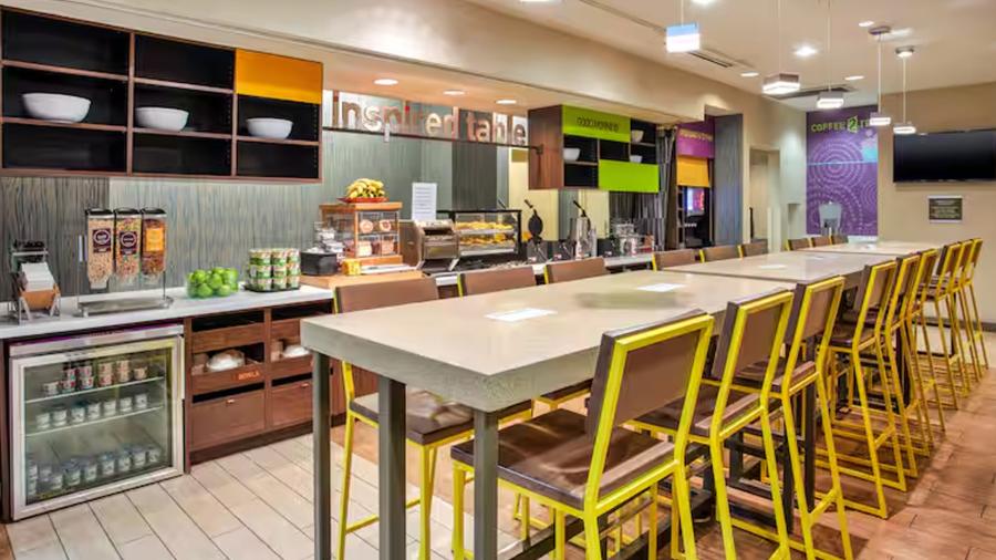 Hotel lobby kitchenette with bright yellow chairs.