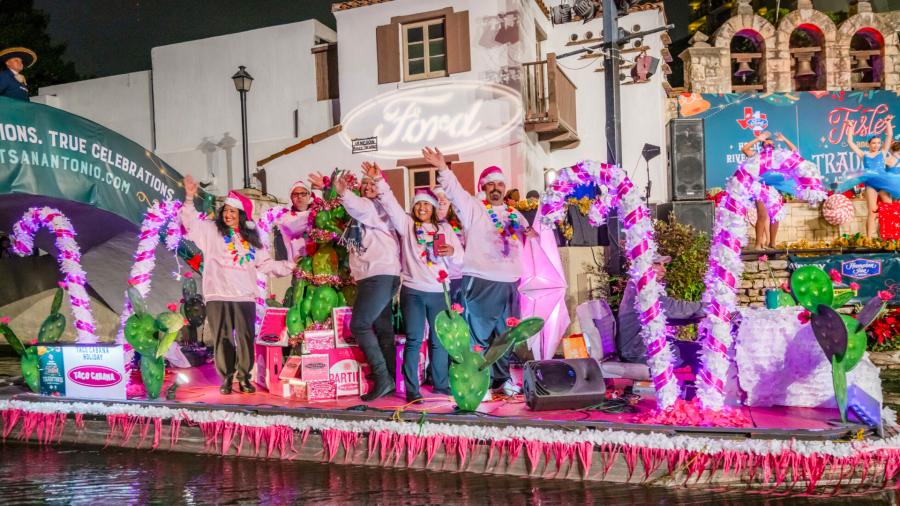 River barge at Ford Holiday River Parade with pink and white candy canes and people dressed in pink sweaters.