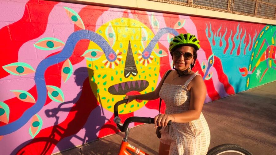 Girl with bike helmet on bike in front of mural