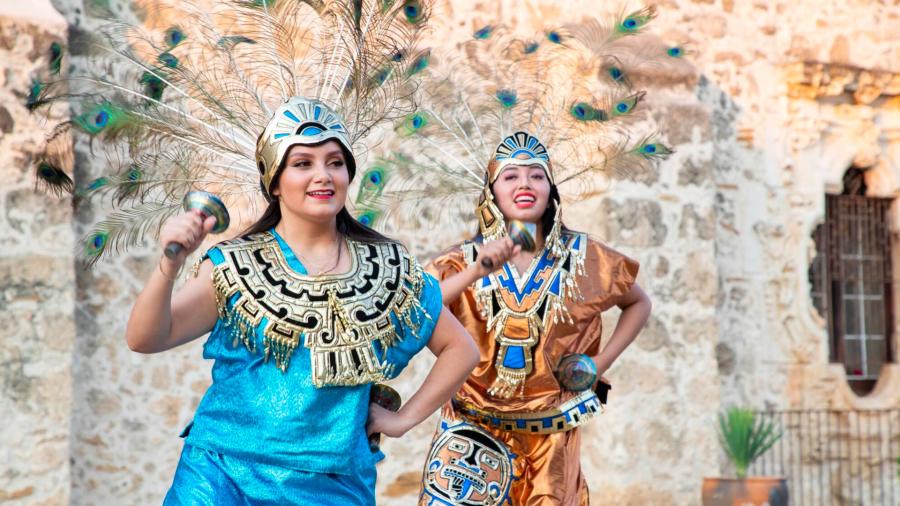 Two women in native dress in front of San Antonio Missions.