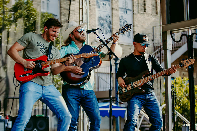 Three musicians playing music in front of microphones.