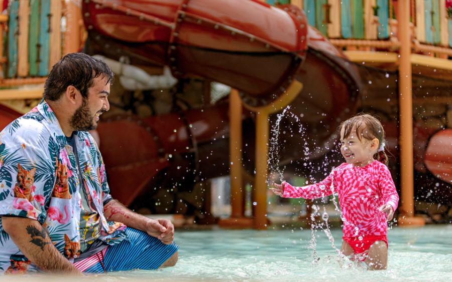 Father and small daughter splashing in water at Schlitterbahn.