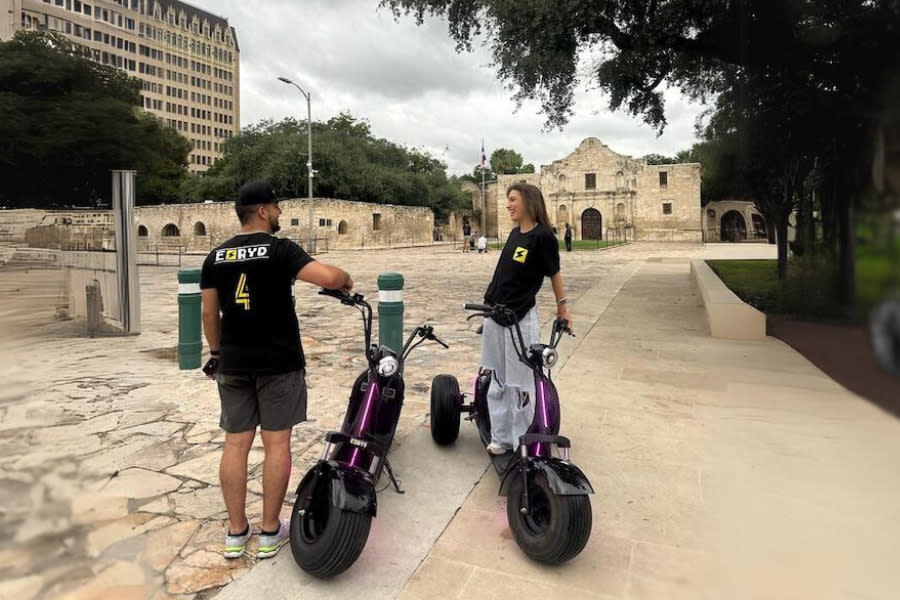 people in front of alamo with electric scooters