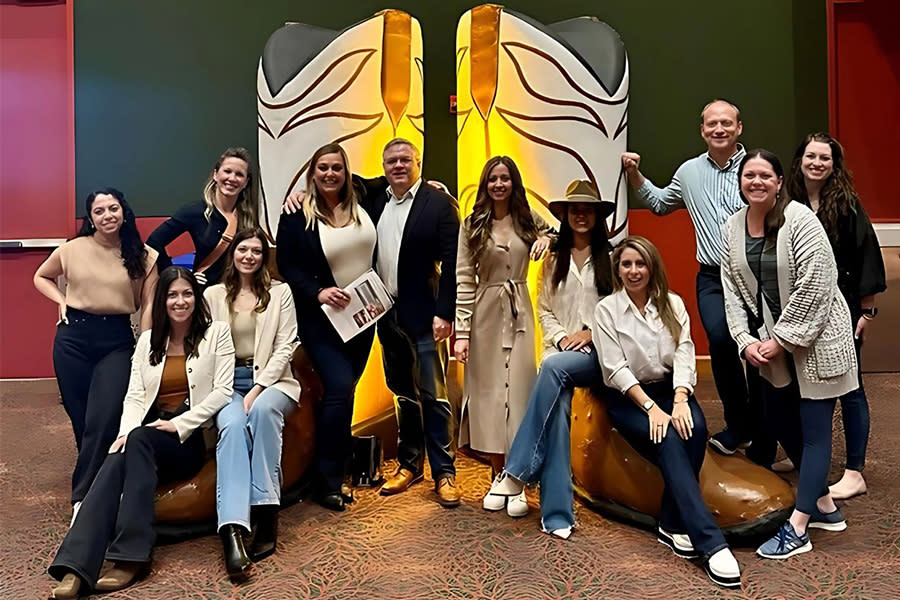 Group of team members in front of replica of cowboy boots artwork