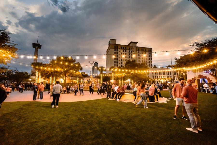 Large outdoor gathering at dusk with decorative lighting