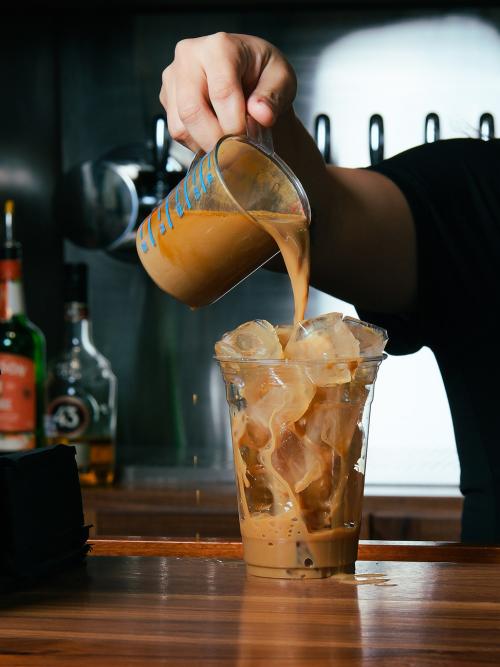 Hand pouring iced coffee at Big Aztec Corner Bar in San Antonio.