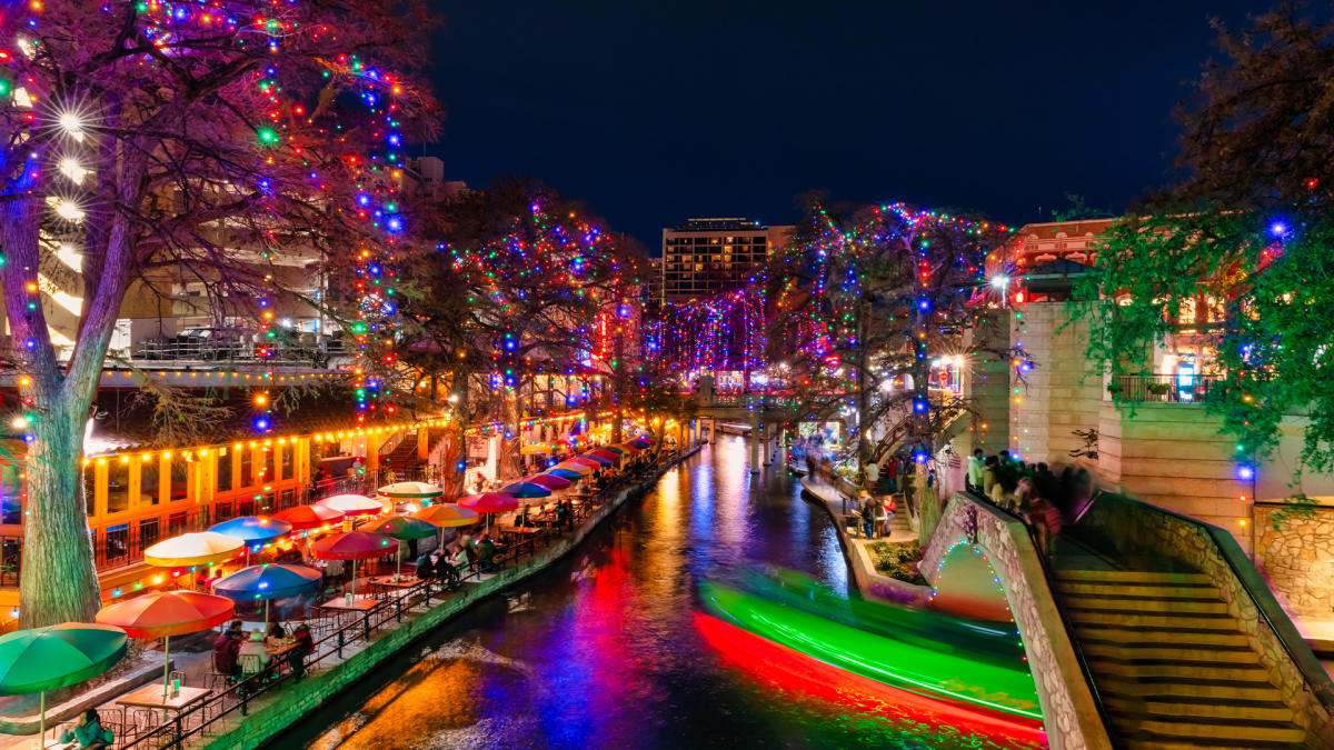 The San Antonio River Walk lit up at night with holiday lights.