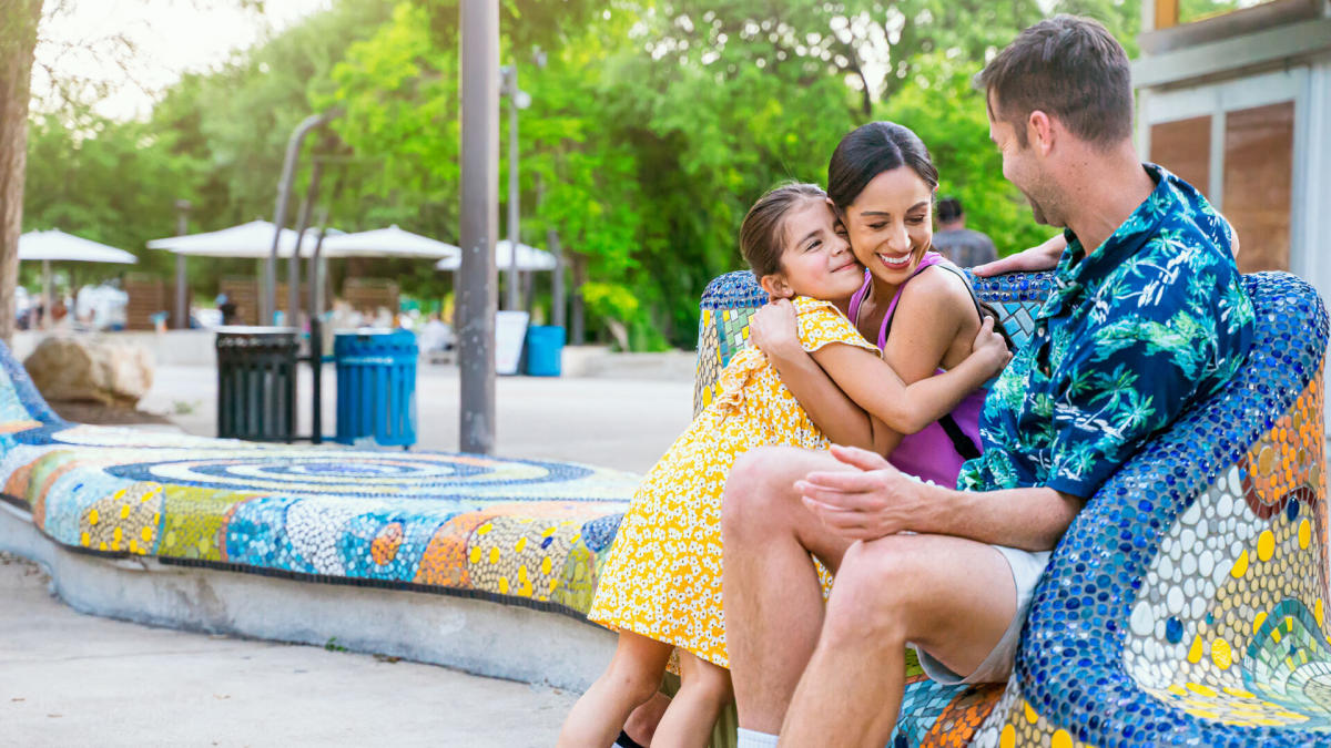 Mother hugging daughter in front of dad