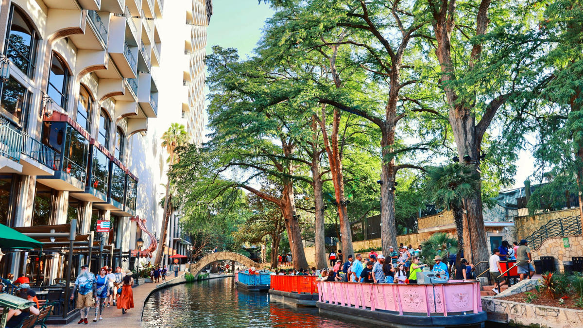 River barges on San Antonio River Walk floating by hotels.