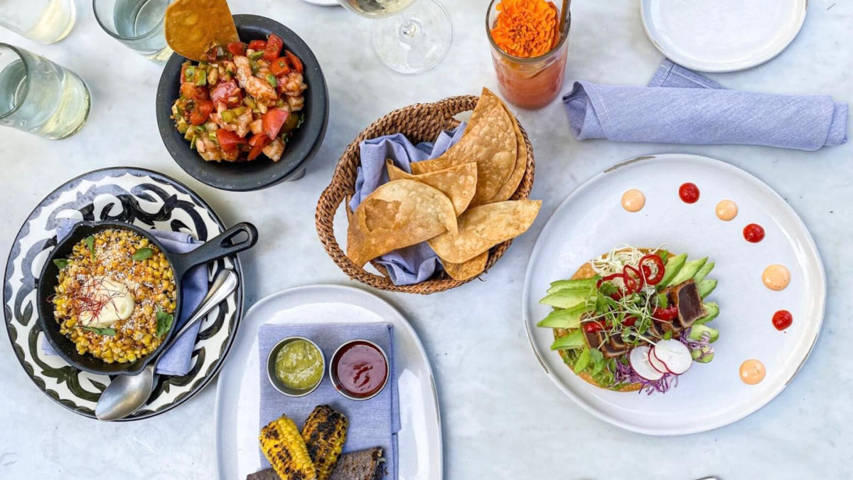 Overhead view of food spread with skillet corn, chips, and plated meal
