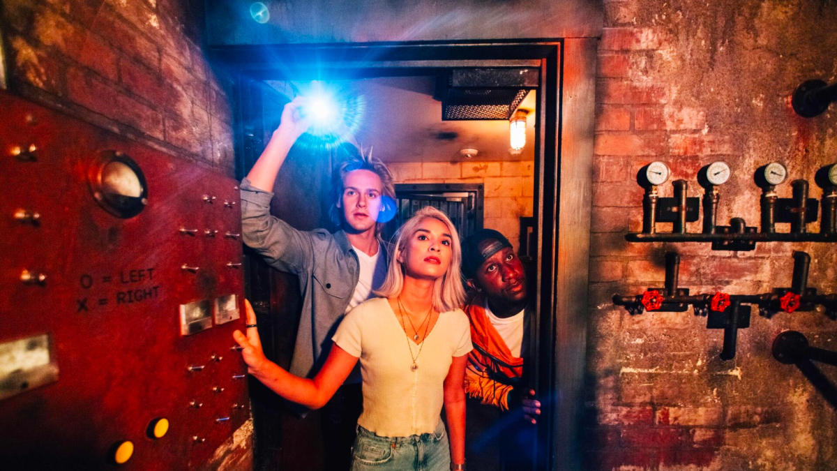 Girl and two boys opening door and holding flashlight.