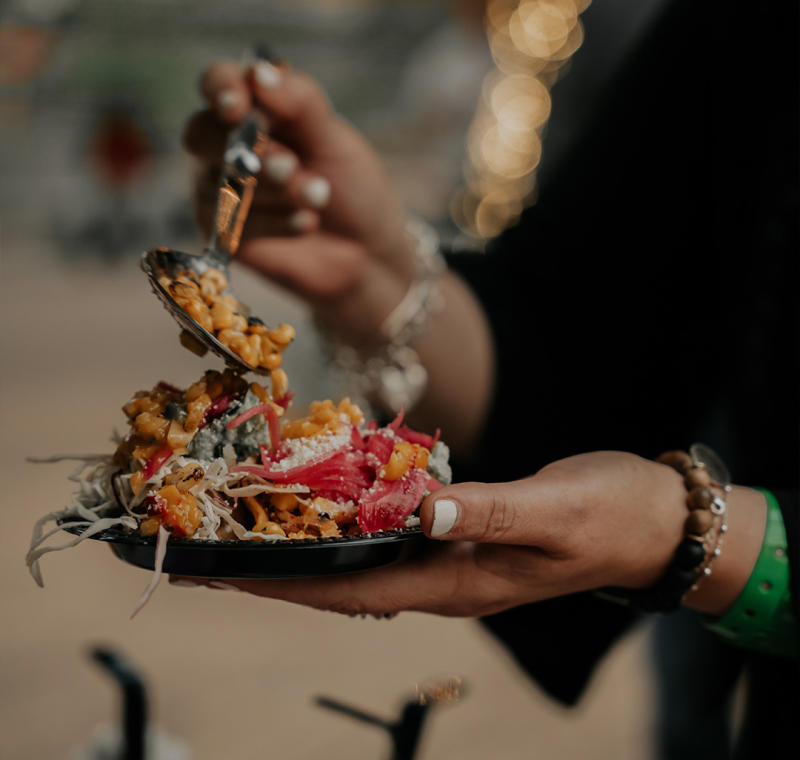 Person's hands holding plate of food and spoon.