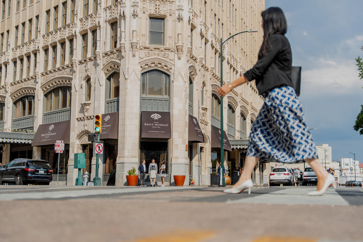 Woman in professional clothing walking in front of the Emily Morgan Hotel.