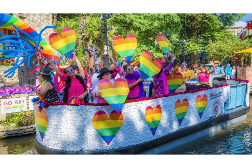 River barge with rainbow hearts and people floating on River Walk