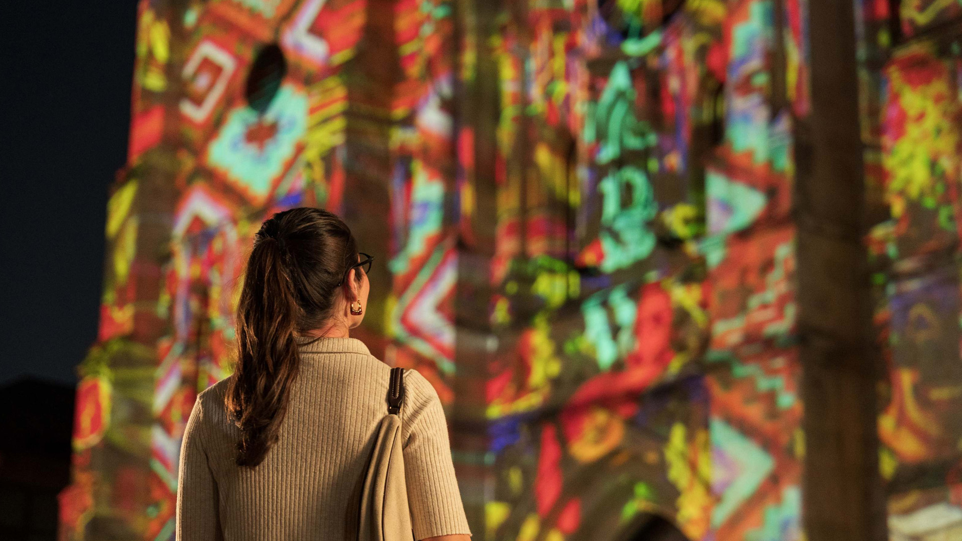 Woman looking up at lightshow at San Fernando Cathedral in San Antonio.