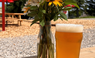 a glass of beer and a vase full of flowers at Kingsley Local Brewing