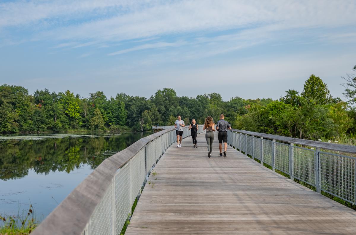 People jogging along the bridge at the Boardman Lake loop trail.