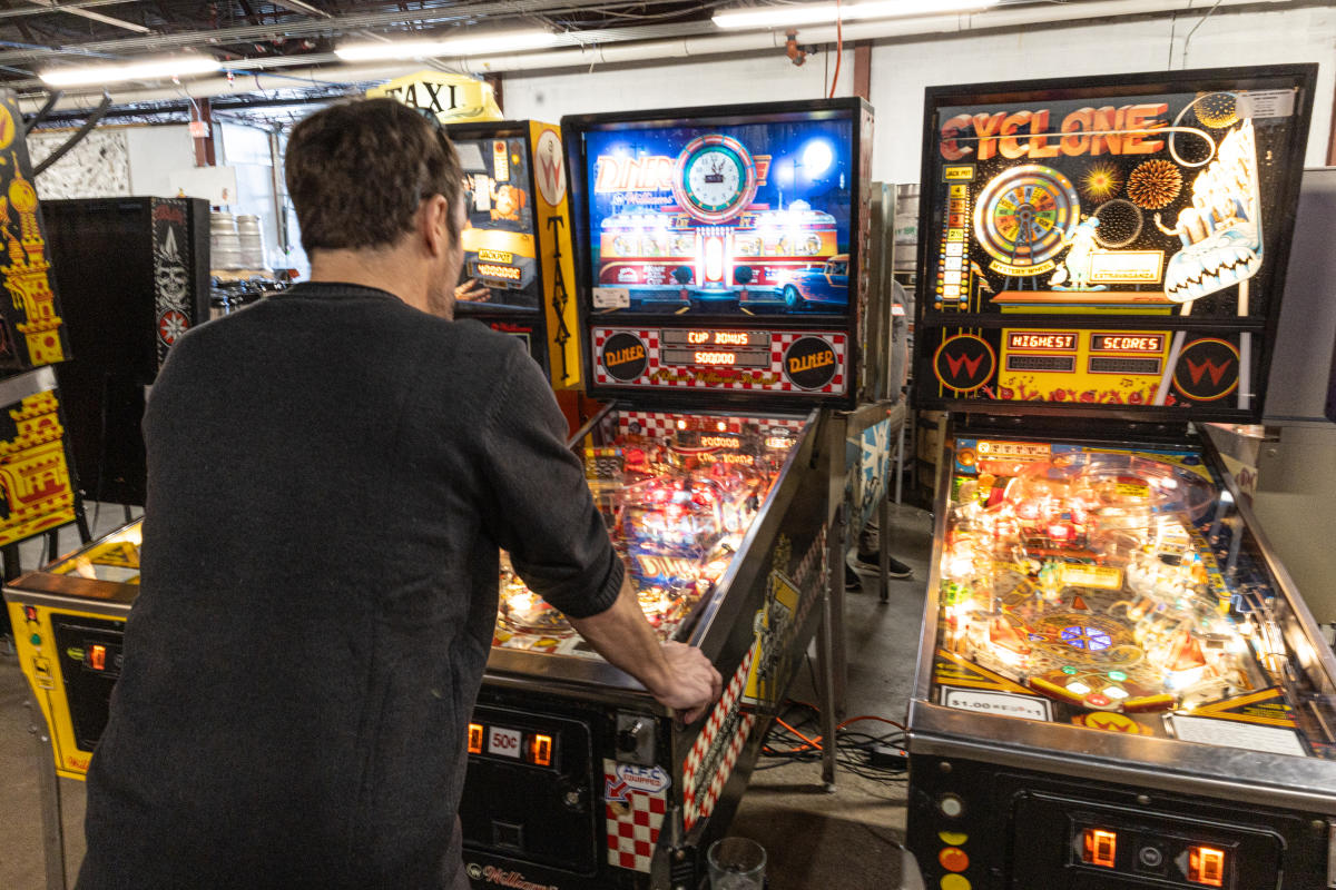 Man playing pinball at Right Brain Brewery