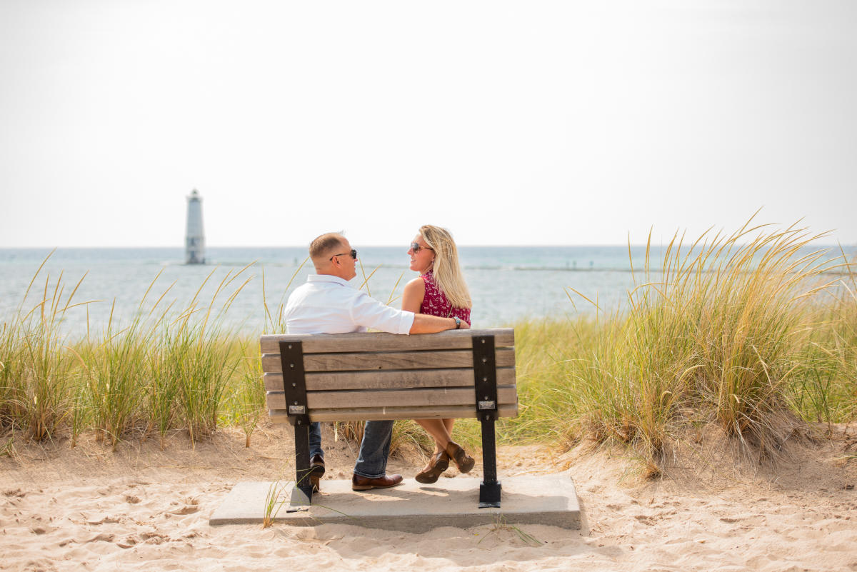 Couple Sitting On A Bench overlooking Frankfort Beach in Traverse City, MI
