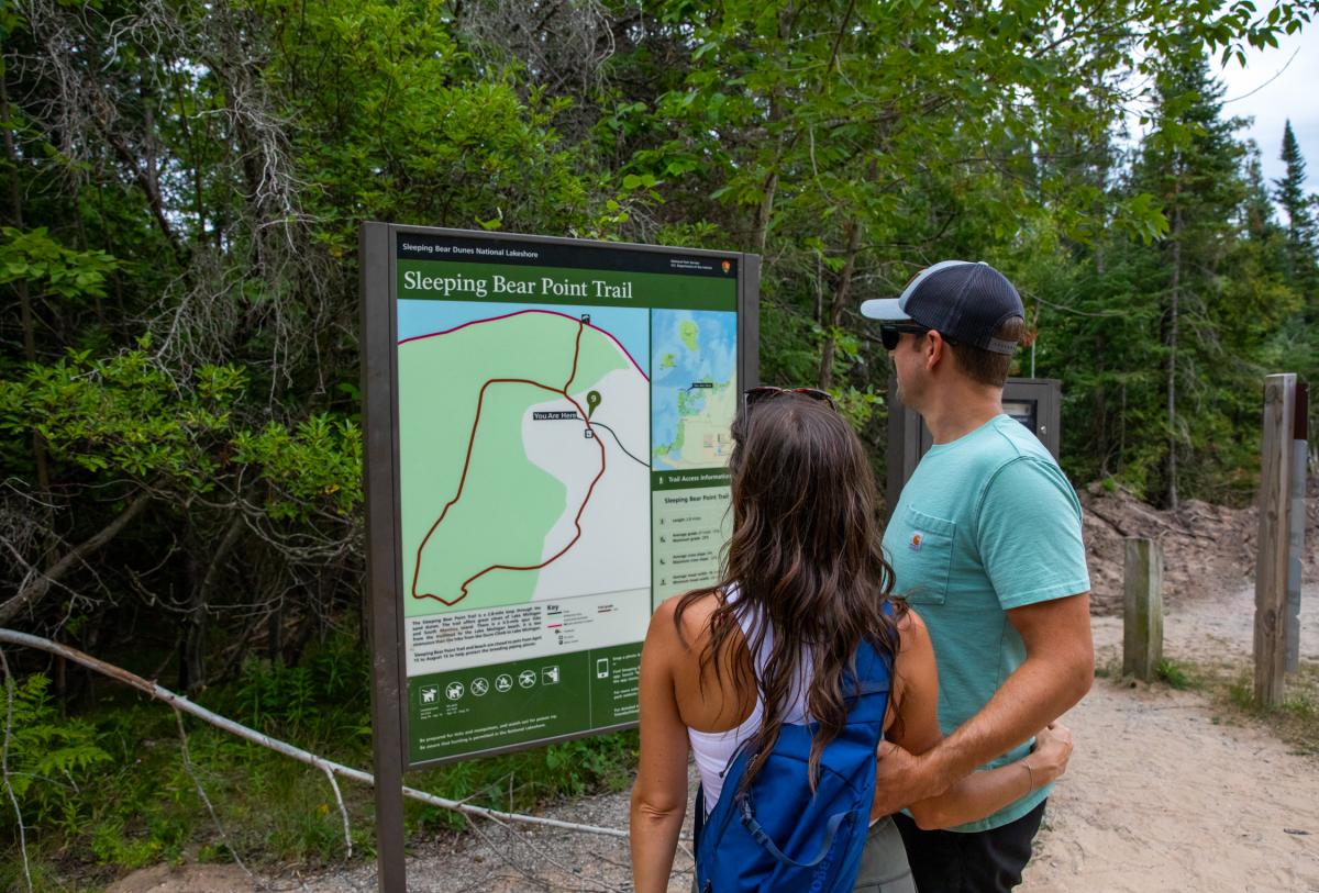 Couple looking at Sleeping Bear Point Trail map sign
