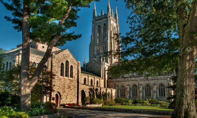 Side view of the Bryn Athyn Cathedral, the bell tower is surrounded by green trees.