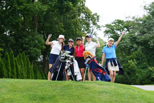 5 women golfers pose on a golf course