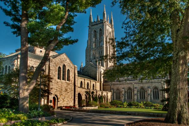 Side view of the Bryn Athyn Cathedral, the bell tower is surrounded by green trees.