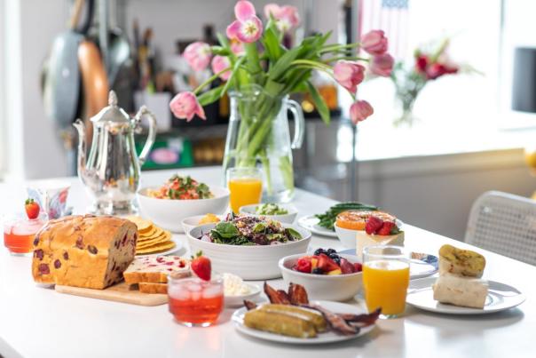 Various brunch plates, oragne juice, pink cocktails, tea pot, and flowers