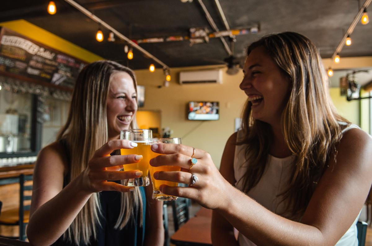 Two women laughing and drinking beer at Round Guys Brewing