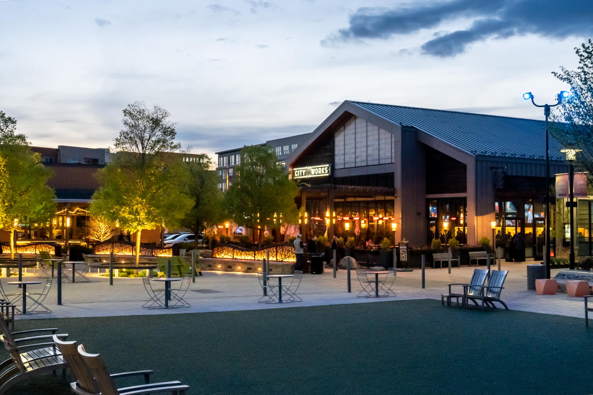 Photo of City Works Restaurant’s vibrant outdoor dining area at dusk with illuminated trees and inviting, cozy seating.