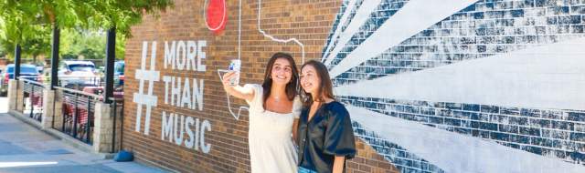 Two girls taking a selfie at Toyota Music Factory wall mural