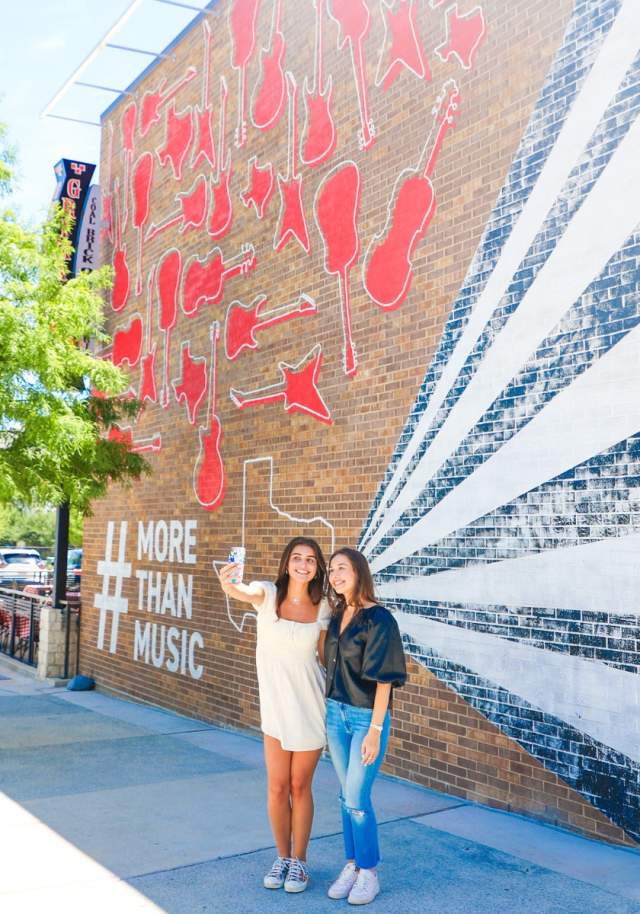 Two girls taking a selfie at Toyota Music Factory wall mural