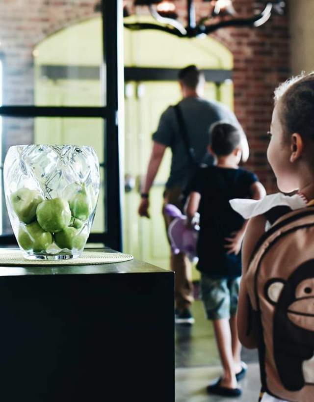 Little girl following her brother and Dad into hotel wearing a monkey backpack