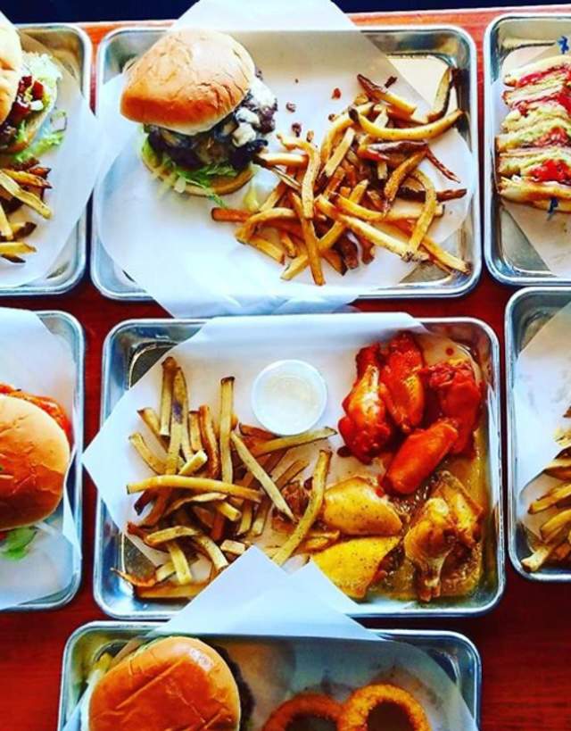Plates of burgers, wings, and fries at Maacs Grill in Irving, TX