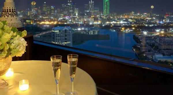 Candlelit table with wine glasses at The Constellation Club, overlooking city lights.