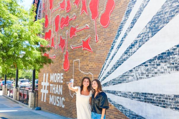Two girls taking a selfie at Toyota Music Factory wall mural