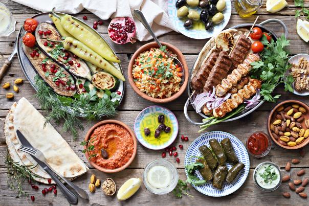 Grilled meats, vegetables, hummus, olives, and Mediterranean dishes on table