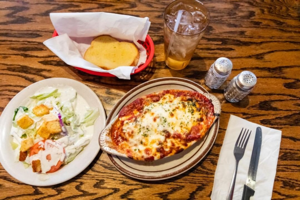 Italian pasta dish with a side salad and garlic bread from Angelos in Irving, TX