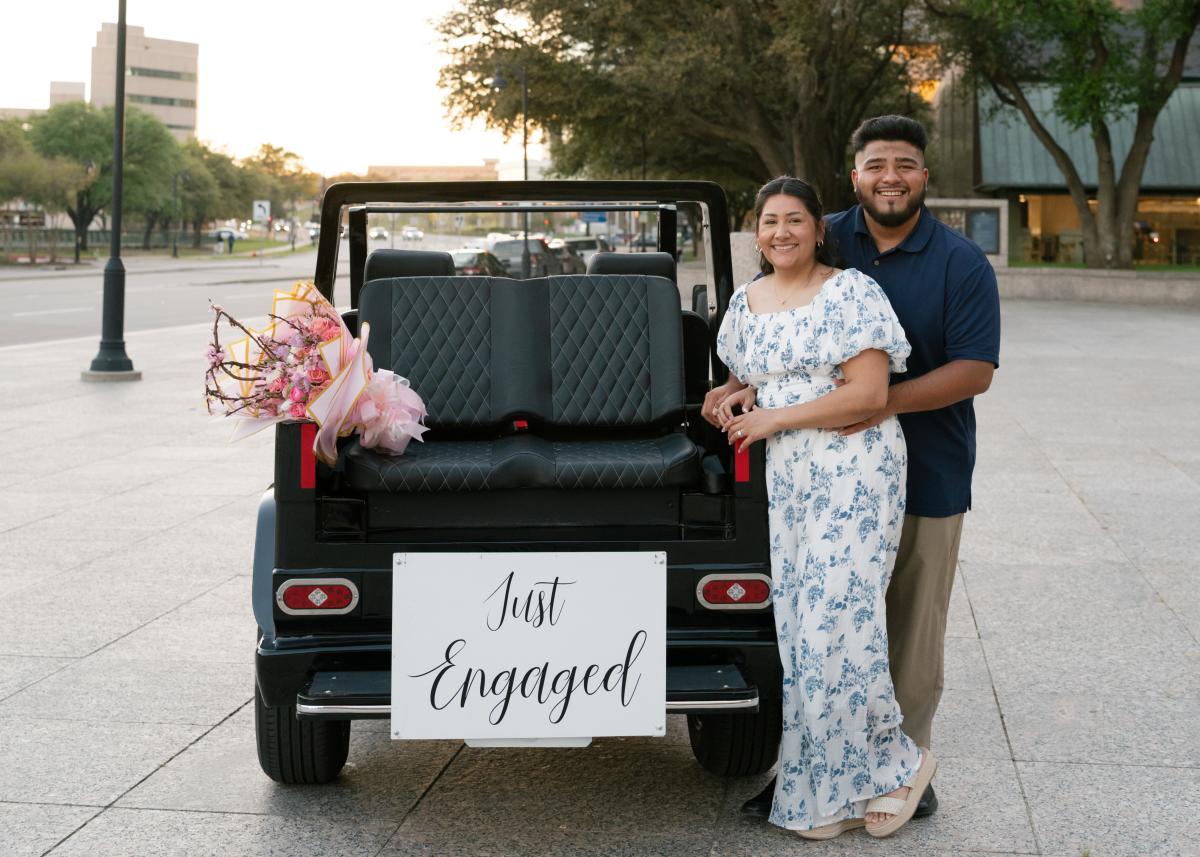 Man and women standing infront of a just engaged sign after proposal