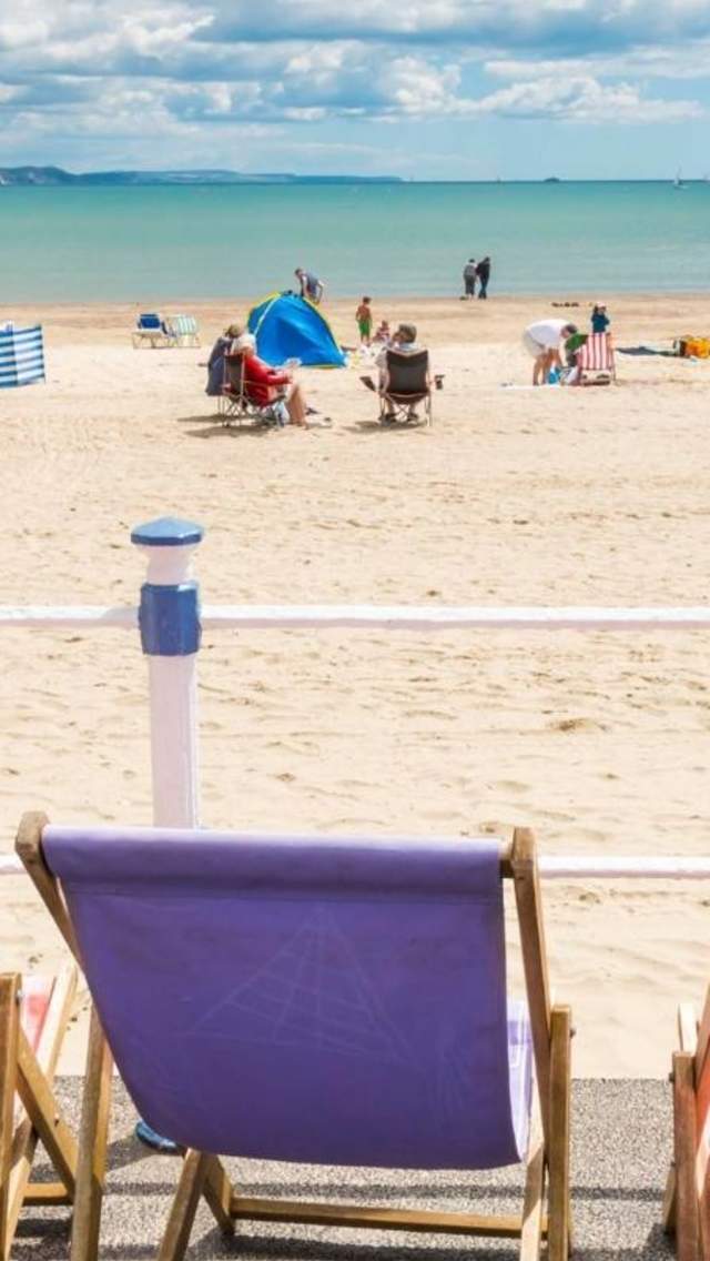 Colourful deckchair on the promenade at Weymouth Beach, looking onto the beach